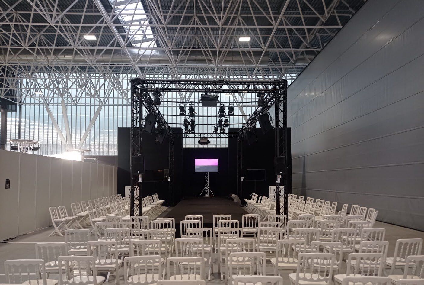 Plateau monté dans un hall de parc des expositions : structure, diffusion accrochée, éclairage et écran face public.