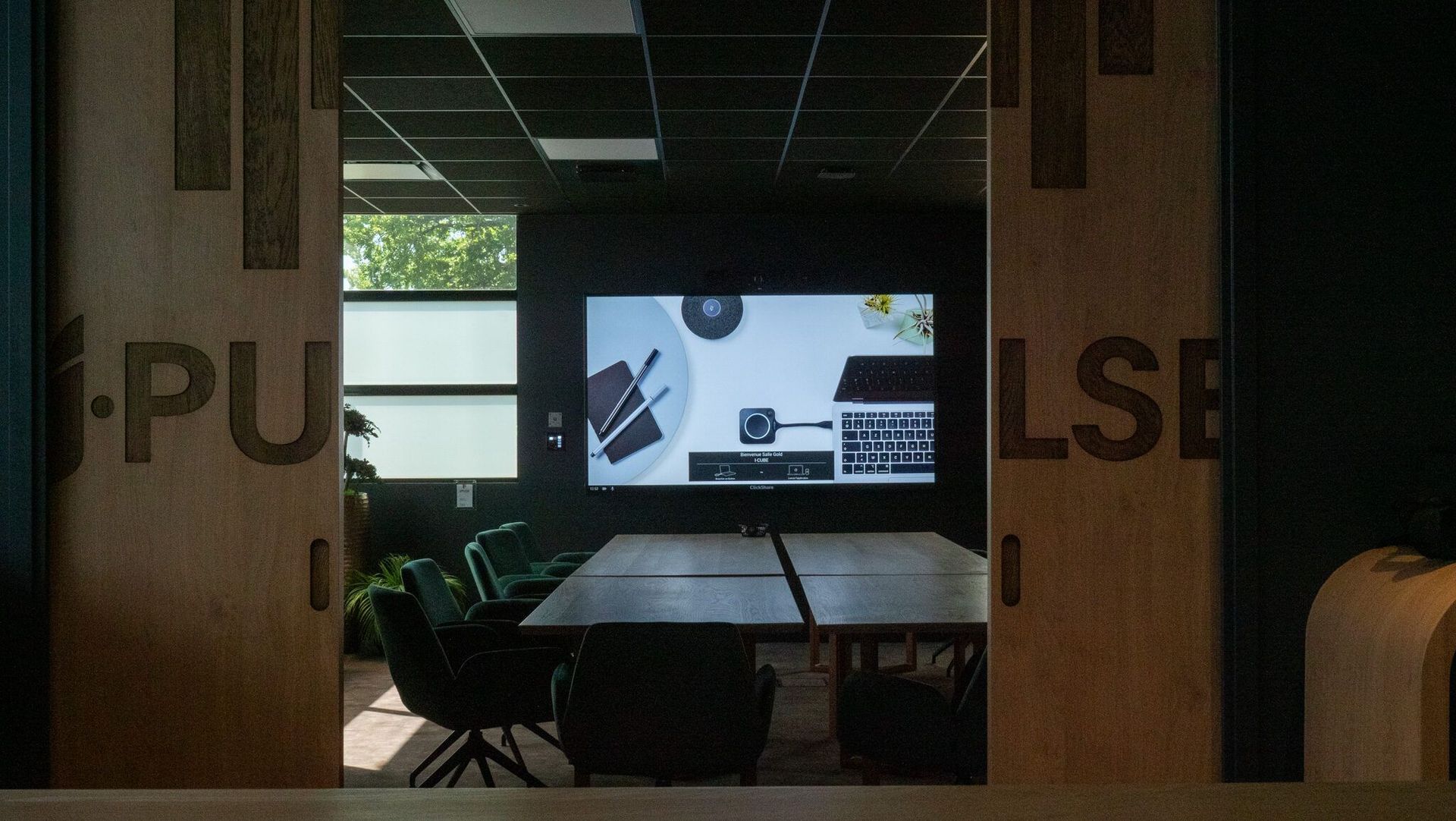Salle de réunion équipée pour la visioconférence : écran, caméra, micro de plafond et partage d’écran sans fil Barco ClickShare.